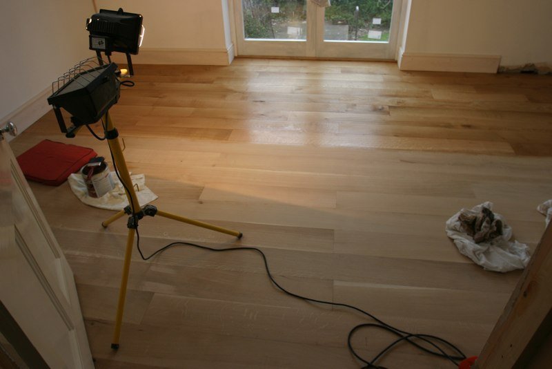 New oak flooring being laid in a freshly plastered room