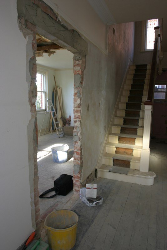 A first floor room stripped to brick and plasterboard, looking through to the staircase